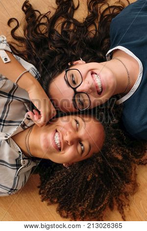 Two teenage best friend girls lying in the ground cheek to cheek