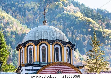 Rila monastery, Bulgaria church dome and cross close-up and autumn mountain trees at background