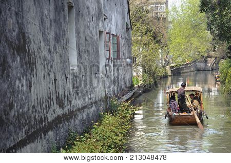 SUZHOU, CHINA - MARCH 31, 2013 - Traditional rowing boat taking tourists along the canal on Pingjianglu, Suzhou, China