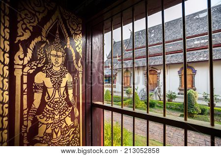 CHIANG MAI, THAILAND - MARCH 11, 2015 - Gold-painted Buddha image on a wooden shutter inside the main Wiharn of Wat Chiang Man, Chiang Mai, Thailand