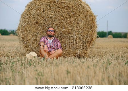 man resting after hay harvesting in haystacks
