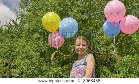 Cheerful and pretty girl with colorful balls attached to her hair and braids on her head. Funny idea with balloons