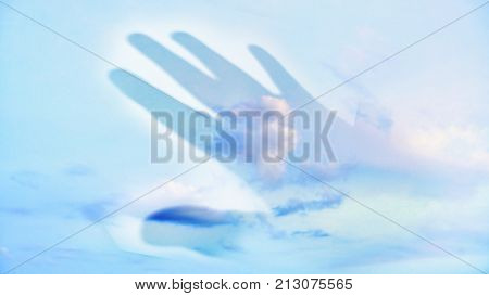 Abstract transparent hand shadow touching blue sky and white clouds. Soft focus with space for add text.