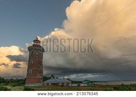 Lighthouse and house in the Baltic Sea. Shore evening light sunset clouds and architecture concept. Mohni small island in Estonia Europe.