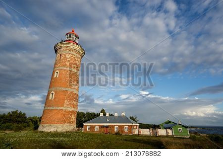 Lighthouse and house in the Baltic Sea. Shore evening light sunset clouds and architecture concept. Mohni small island in Estonia Europe.