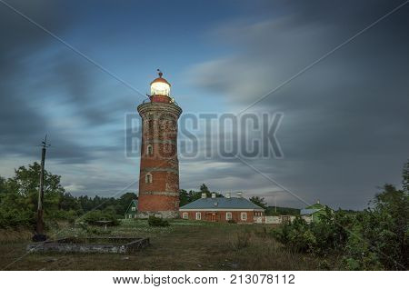 Lighthouse and house in the Baltic Sea. Shore evening light sunset clouds and architecture concept. Mohni small island in Estonia Europe.