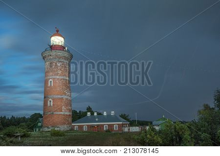 Lighthouse and house in the Baltic Sea. Shore evening light sunset clouds and architecture concept. Mohni small island in Estonia Europe.