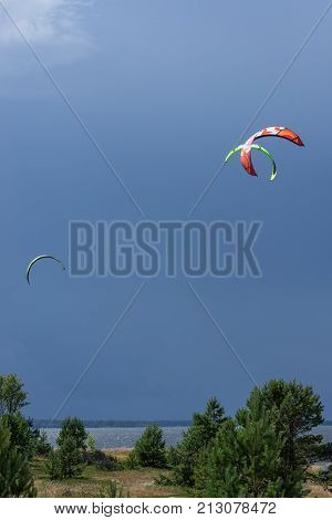A kite surfer rides on the sea. Kites in the sky. Kite Boarding extreme sport on Mohni small island in Estonia Europe.