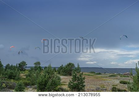 A kite surfer rides on the sea. Kites in the sky. Kite Boarding extreme sport on Mohni small island in Estonia Europe.
