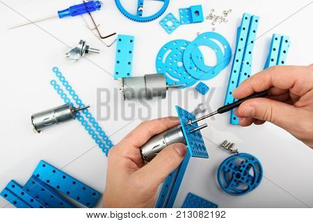 Modeling hobby concept. Hands putting screw in metal rc car parts