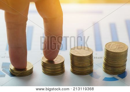 Finance capital banking and accounting growing up concept finger step on money coins staced on paper graph