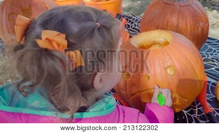 Little girl carwing pumpking in the park.
