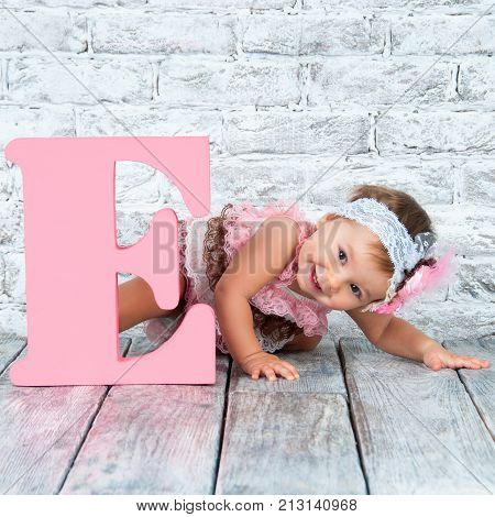 Beautiful and cute girl in pink dress with the letter E. Emotional girl