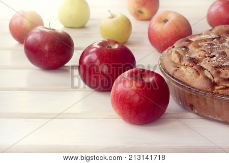 lush and ruddy pie on the background of apples on the table front view