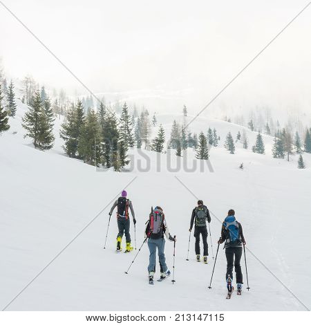 Group of back country skiers walking through a misty valley. Exploring winter fairytale.