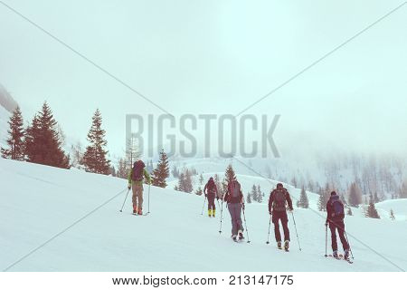 Group of back country skiers walking through a misty valley. Exploring winter fairytale.