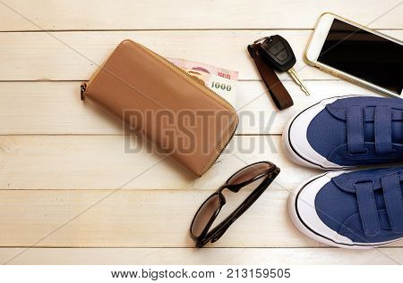 Ready to traveling with blue sneaker ,glasses ,car keys ,money and smartphone on white wood board background ,concept idea for traveling,top view for copy space
