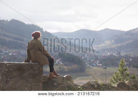 girl hipster sits on the background of Romanian Carpathians mountains