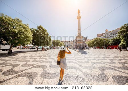 Woman tourist walking on the Pero square with beautiful tiles and column during the sunny day in Lisbon city, Portugal