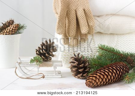Winter Concept With White Blanket Pullover, Gloves, Sleds, Cup, Cones And Fir Branches.