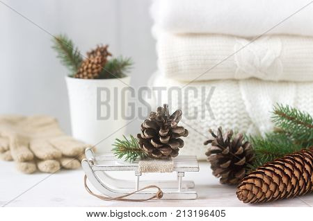 Winter Concept With White Blanket Pullover, Gloves, Sleds, Cup, Cones And Fir Branches.