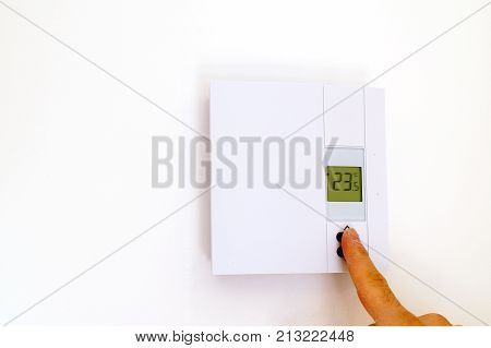 Finger adjusting thermostat in house in celcius