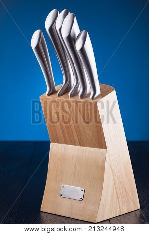 steel knifes in wooden block on the blue background