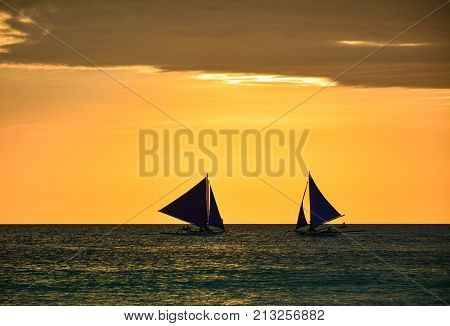 BORACAY PHILIPPINES - JANUARY 7 2015 - Boats with some tourists watching the sunset from the sea in Boracay island Philippines