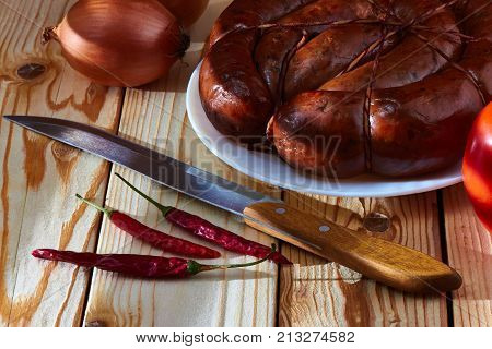 Preparation of a festive table on a table of smoked sausage a tomato onions and acute red pepper to improve apetit.