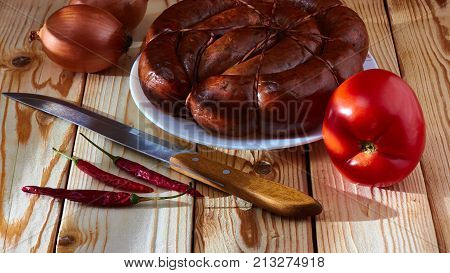 Preparation of a festive table on a table of smoked sausage a tomato onions and acute red pepper to improve apetit.