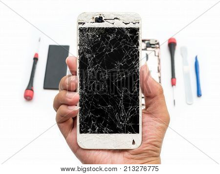Close-up of cracked smartphone screen in technician hand on blurred smartphone component background