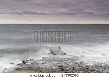 Rocky beach and pier landscape at dusk. Kullaberg Sweden.