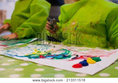 children painting with finger paint on white paper