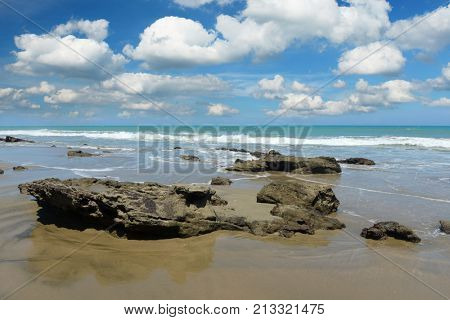 Mancora Beach with rocks in the foreground and clouds