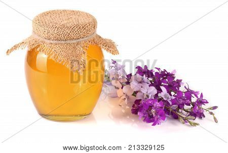 Jar of honey with wildflowers isolated on white background.