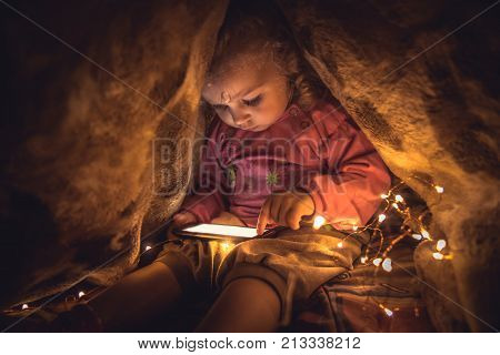 Curious child playing with smart phone hiding in secret place