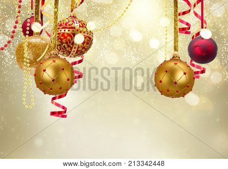 Golden and red christmas balls garland and evergreen fir tree on glowing golden background