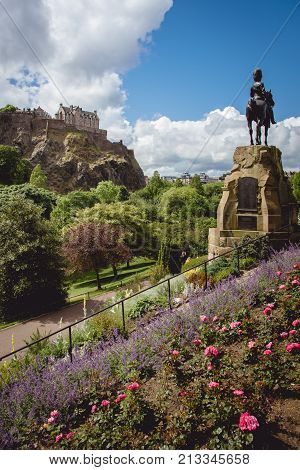 Princes street gardens and the statue of Thomas Guthrie with Edinburgh Castle visible in the background on a beautiful sunny day