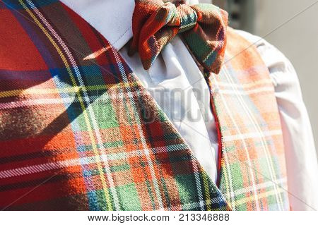 closeup of matching tartan bowtie and waistcoat outdoors in the warm sunlight with a white shirt menswear clothing