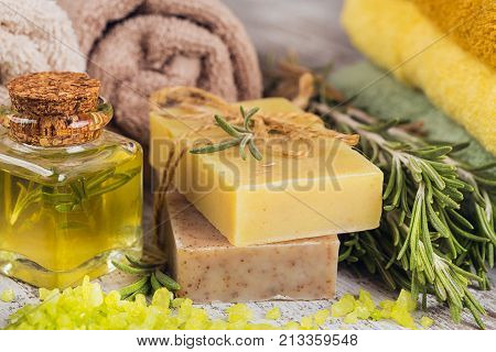 Natural cosmetic oil and natural handmade soap with rosemary on rustic wooden background. Healthy skin care. SPA concept.