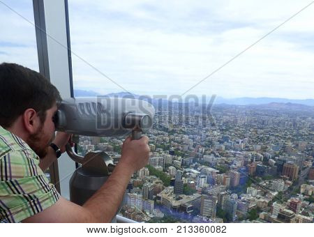 SANTIAGO, CHILE - NOVEMBER 5,2017: Guy looking at the city at "El Mirador" in Santiago, Chile. Man looking at the city through lens at the highest building in South America