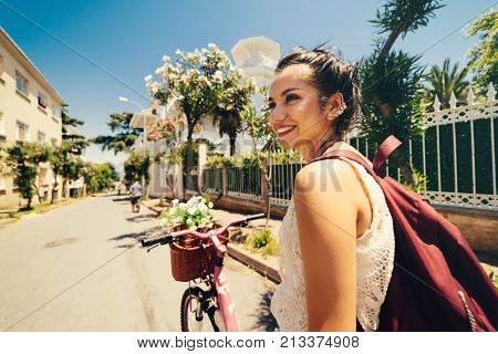 Smiling eastern girl on vintage bicycle with backet of flowers