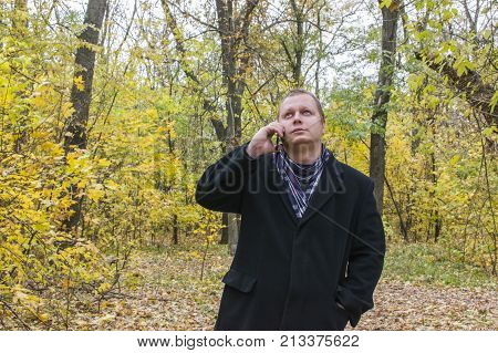Handsome Young Man With A Smartphone On The Street Talking In The Park And Looking Up. Beautiful Aut