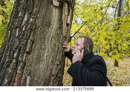 Handsome Young Man With A Smartphone On The Street Talking In The Park And Looking Up. Beautiful Aut