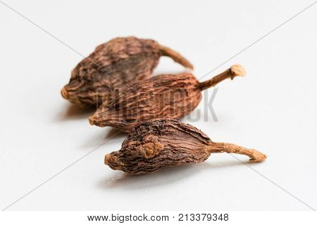 Black Cardamom, latin name: Amomum subulatum on a white surface