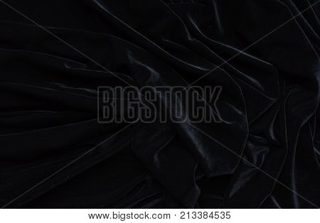 Dark black velvet fabric, wave, draperies. Beautiful textile backdrop to create creative layouts for black Friday. Close-up. Top view