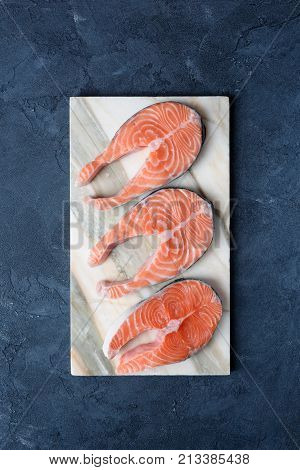Uncooked salmon steaks on marble background. Top view, vertical, copy space for text. Concept of dieting, healthy eating, healthy lifestyle