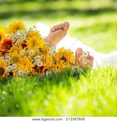 Сhildren`s feet on spring flower against green grass background