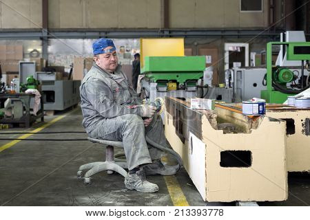 LIPETSK, RUSSIA - JUNE 15, 2017: Lipetsk Machine Tool Plant. The worker polishes the primer layer. Work on the preparation of the machine bed for subsequent painting.