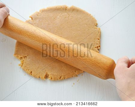 Cooking process. Women's hands rolling the dough for gingerbread man, cookies, shortbread, cakes, pastries, biscuits or pizza with rolling pin. Preparing Christmas treat.